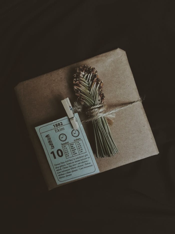 A creatively wrapped package with a vintage tag and dried flowers on a dark background.